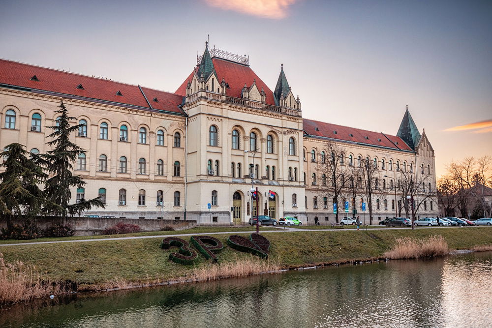 Zrenjanin and the large court building with a river in Serbia surrounded by trees. 