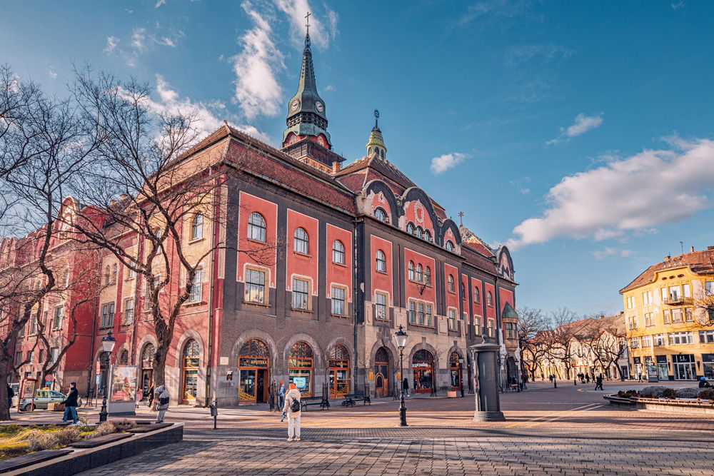 A red brick building with a clock tower stands in Serbia as the town hall of Subotica. 